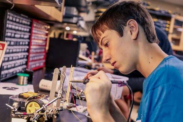 Student soldering wires to make a robot